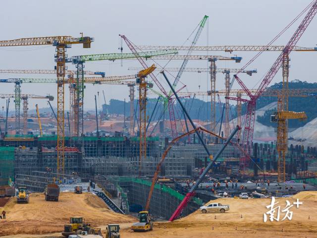 施工现场塔吊林立机器轰鸣，数千名工人、数百台大型机械同时作业。