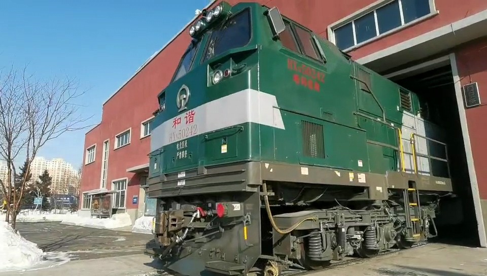 随着出库指令下达,一台hxn5型242号机车缓缓驶出机车检修库